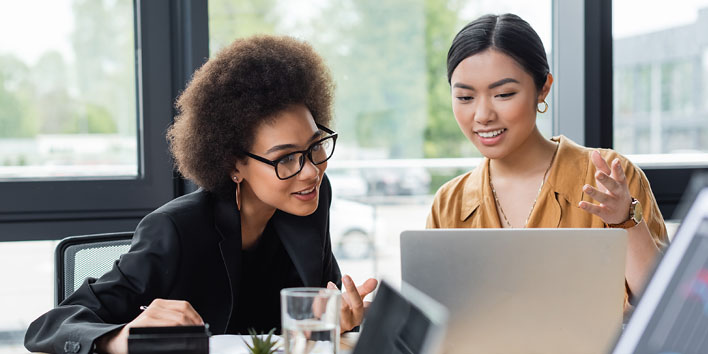 Two businesswomen reviewing their work on a laptop